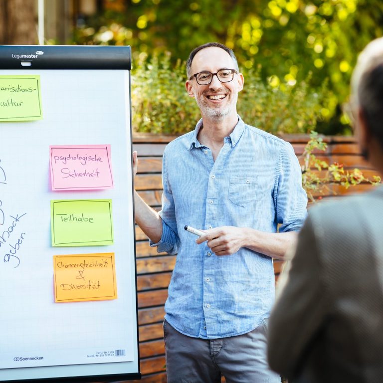 Daniel Craffonara präsentiert bunte Notizen an einem Flipchart in einer natürlichen Umgebung.