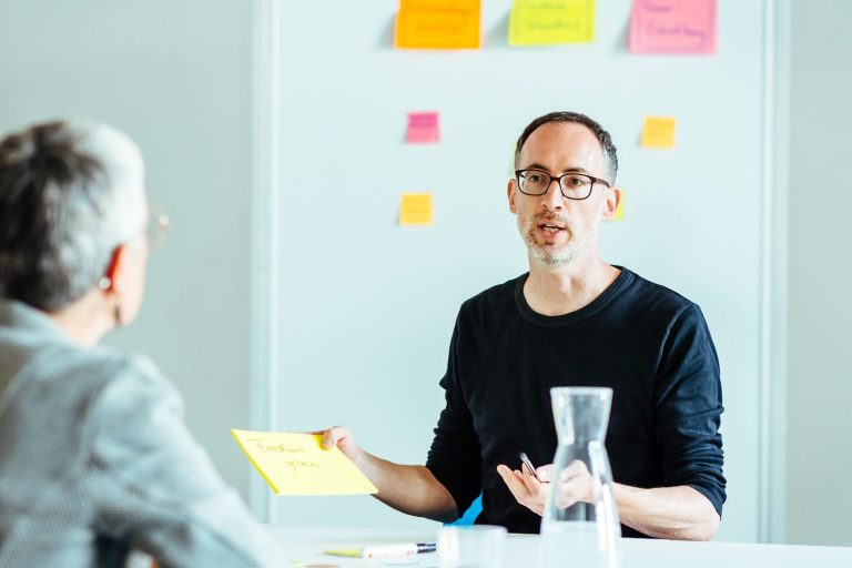 Daniel Craffonara im Gespräch mit zwei Führungskräften – vor einem Flipchart mit Ideen zum Thema Leadership.